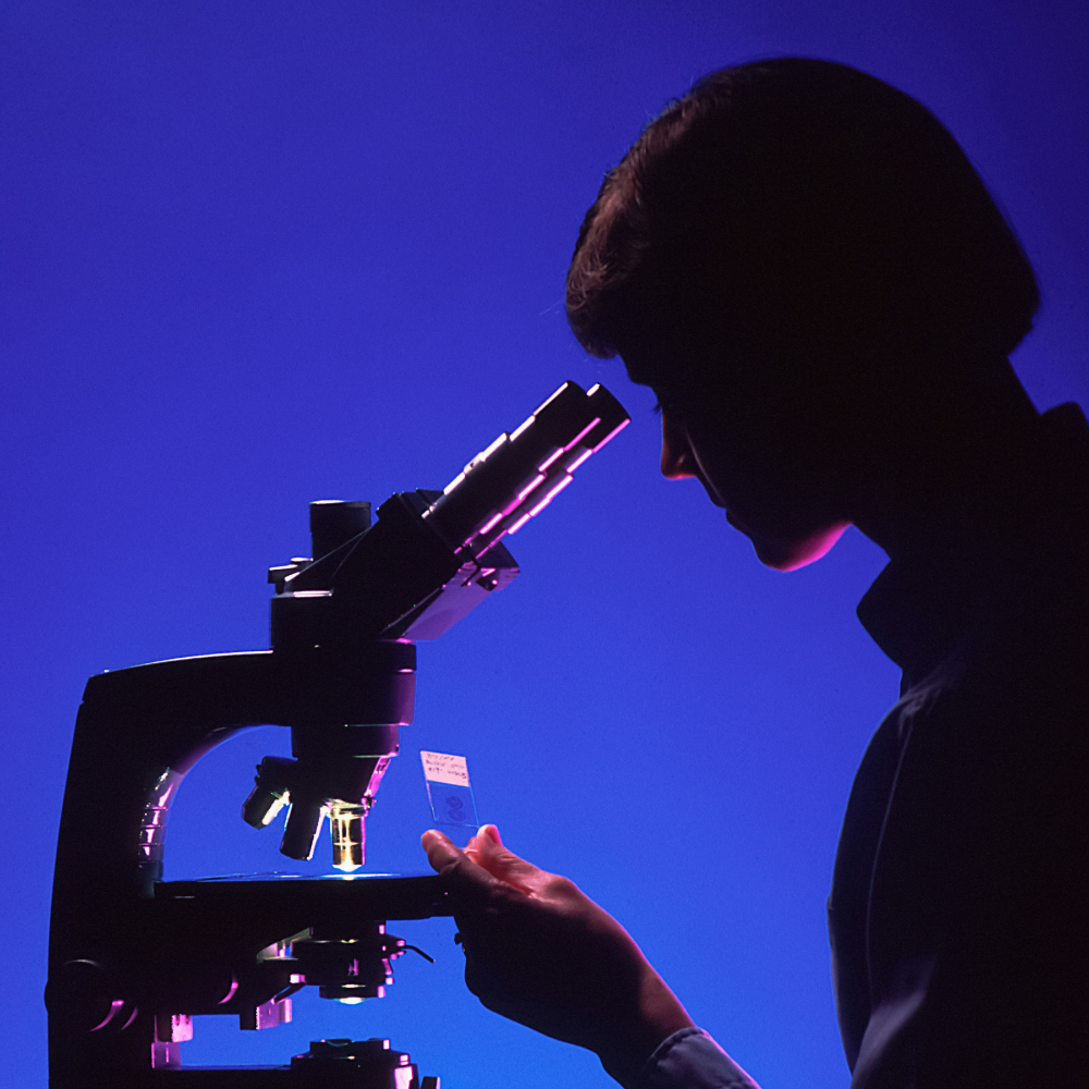 Perioden Simulator Forschung: Person am Mikroskop untersucht die Technologie hinter dem Perioden Simulator